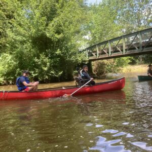 Canoe CIH Jeunes : Un adulte et un jeune en fauteuil descendent un cours d'eau en canoë